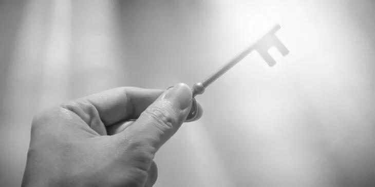 hand holding a key towards the rays of sunlight